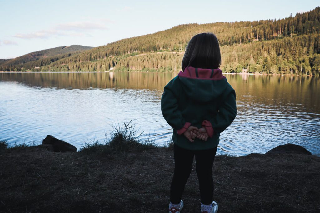 Enfant de dos admirant le lac Titisee en Allemagne lors d'un road trip en famille en van