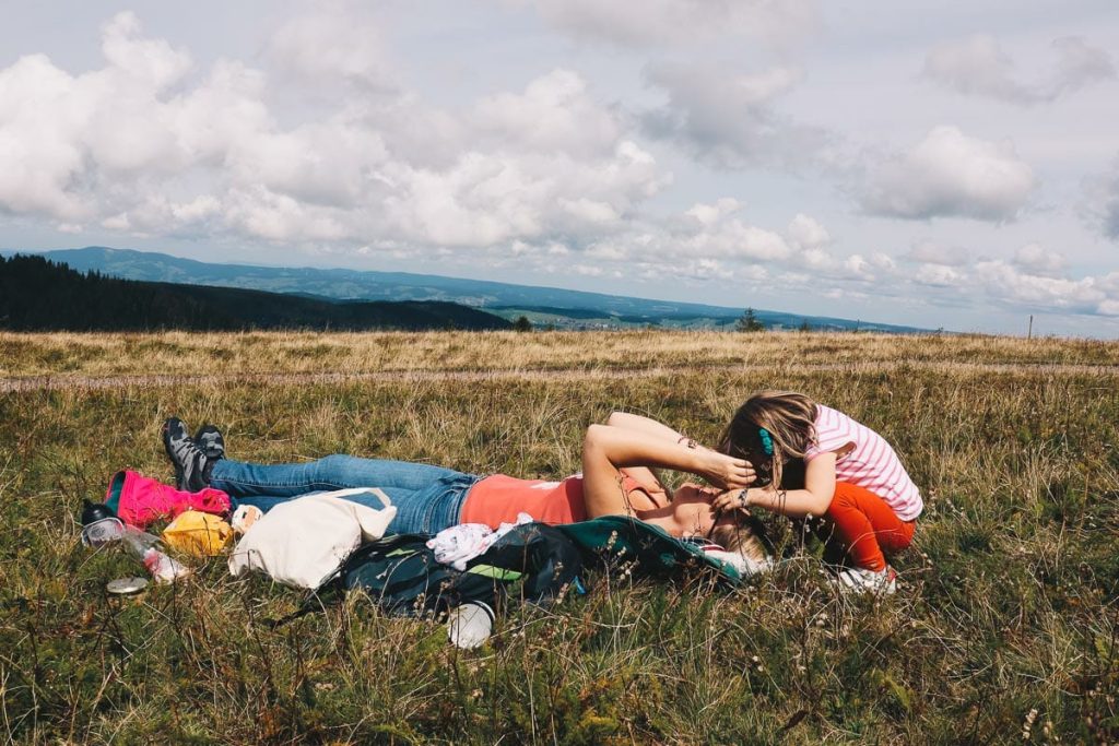 Mère et fille allongées dans l'herbe au sommet du Feldberg en Forêt Noire lors d'un road trip en van en Allemagne