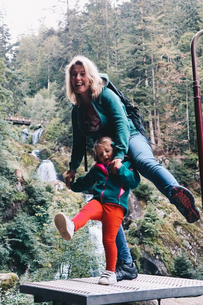 Mère et fille s'amusant à faire des acrobaties sur une plateforme devant les cascades de Todtnau en Allemagne lors d'un road trip en van