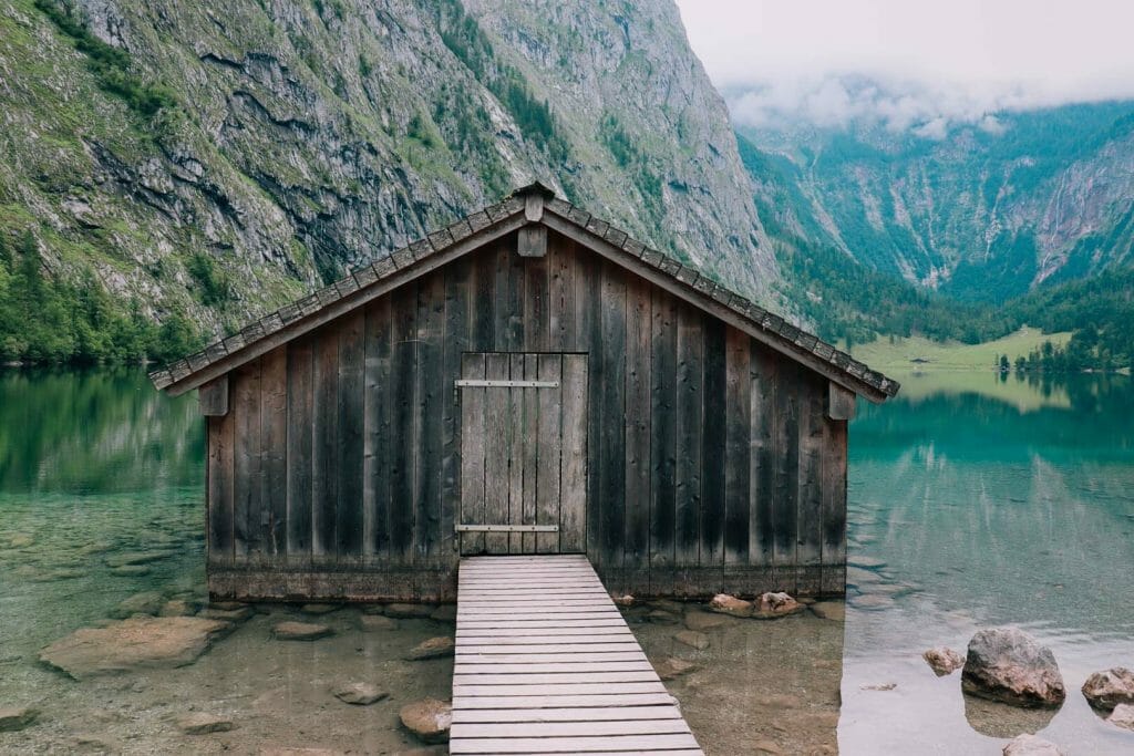 Cabane de pêcheur traditionnelle en bois sur pilotis avec son ponton au-dessus des eaux cristallines du lac Obersee en Bavière