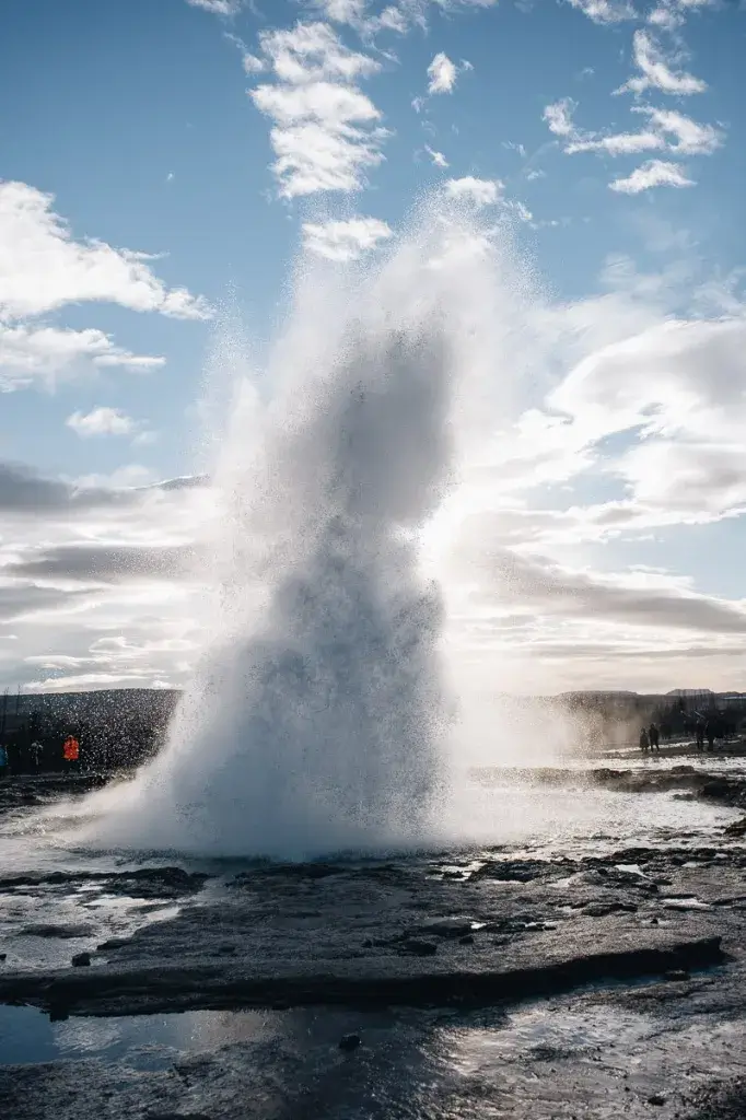 Puissante éruption verticale du geyser Strokkur sous un ciel bleu au Cercle d'Or.