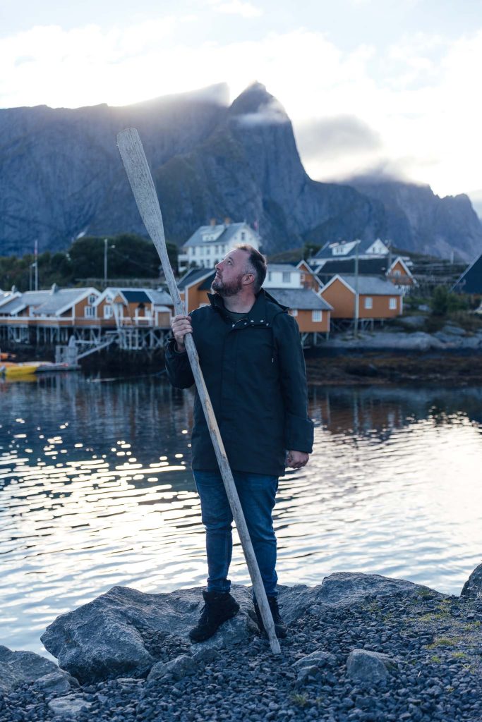 homme tenant une rame à la main dans le port de Sakrisøy