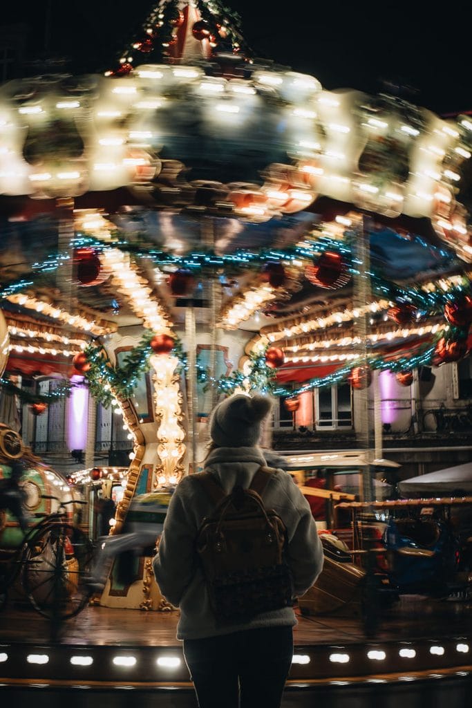 Jeune femme admirant les lumières du carrousel pendant les festivités de Noël à Nancy