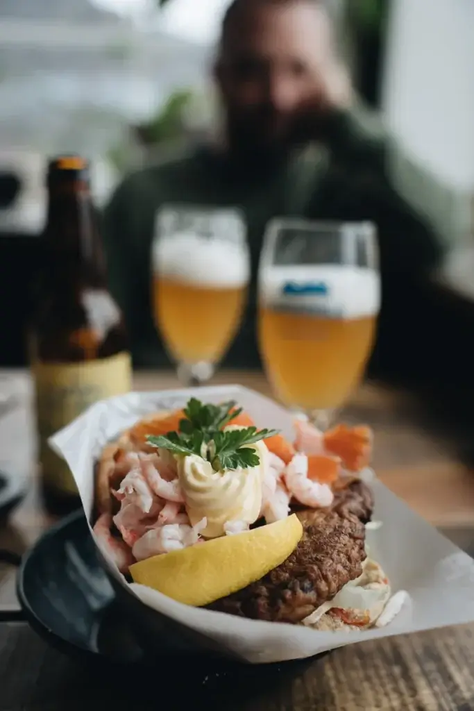 Fish-burger aux crevettes et au saumon servi avec une bière locale, une pause gourmande aux îles Lofoten