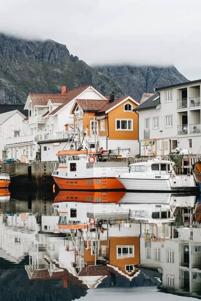 Maisons colorées et bateaux de pêche se reflétant dans le port d'Henningsvær aux îles Lofoten