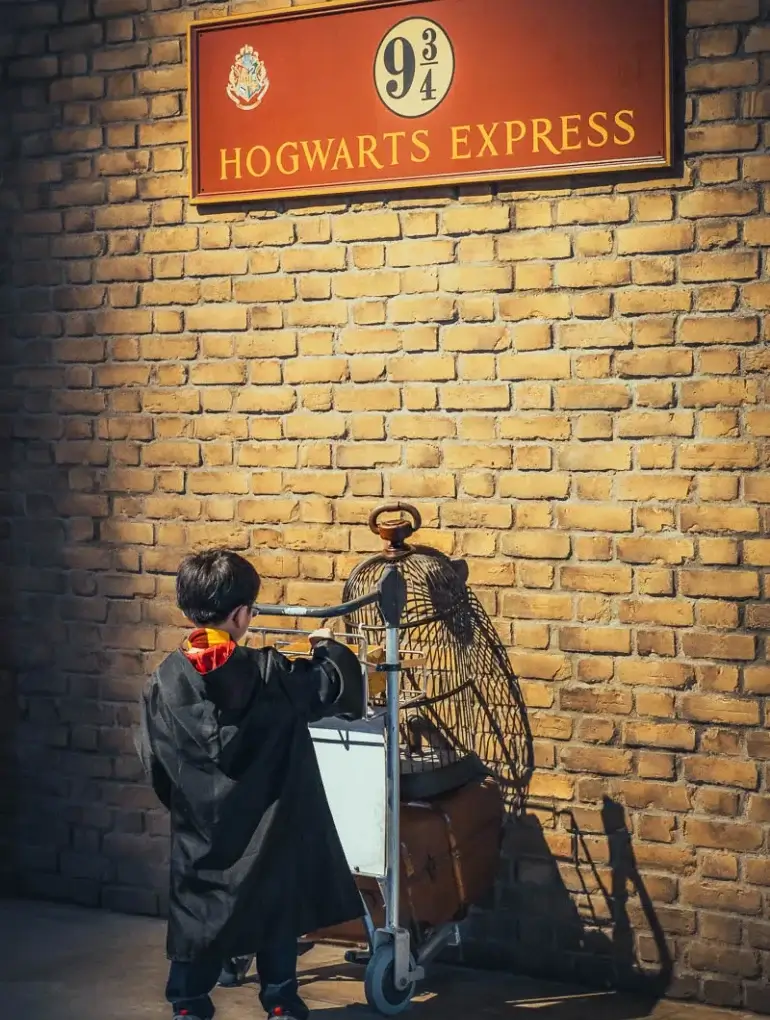 Enfant en robe de Gryffondor poussant le chariot de la voie 9 ¾ au studio Harry Potter de Tokyo
