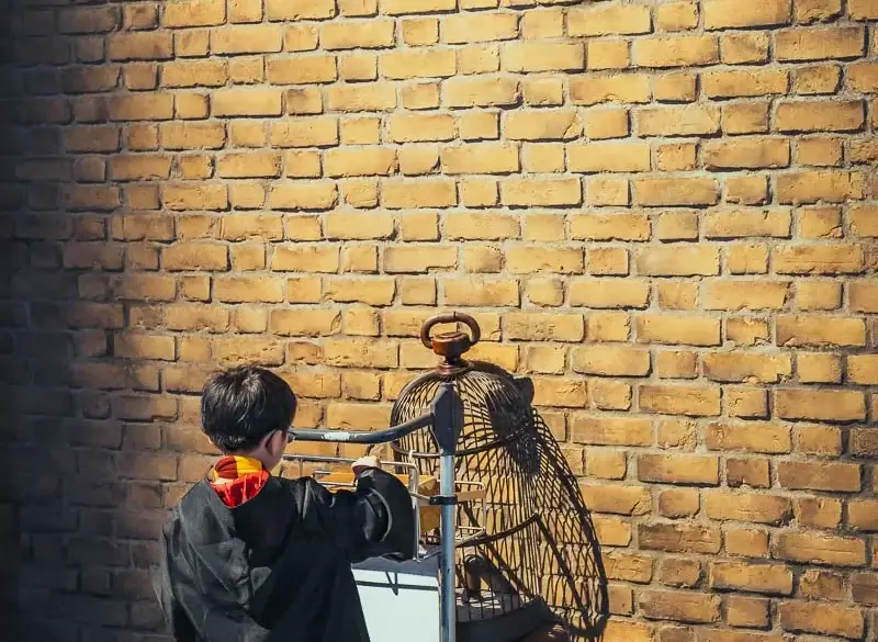 Enfant en robe de Gryffondor poussant le chariot de la voie 9 ¾ au studio Harry Potter de Tokyo