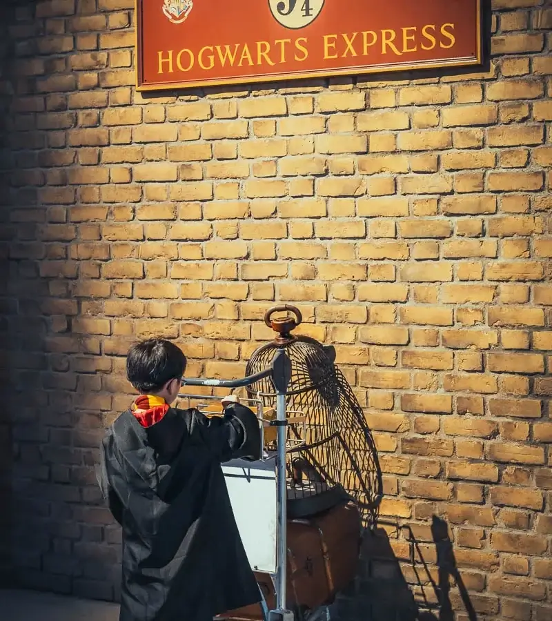 Enfant en robe de Gryffondor poussant le chariot de la voie 9 ¾ au studio Harry Potter de Tokyo