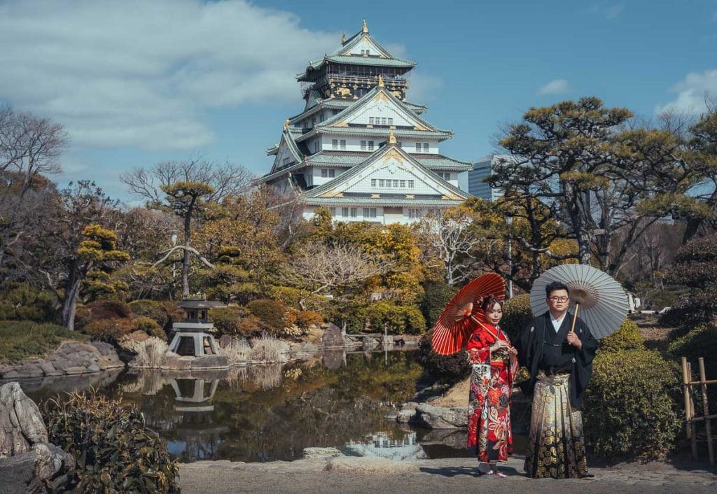 couple de jeunes mariés japonais posant devant le château d'Osaka