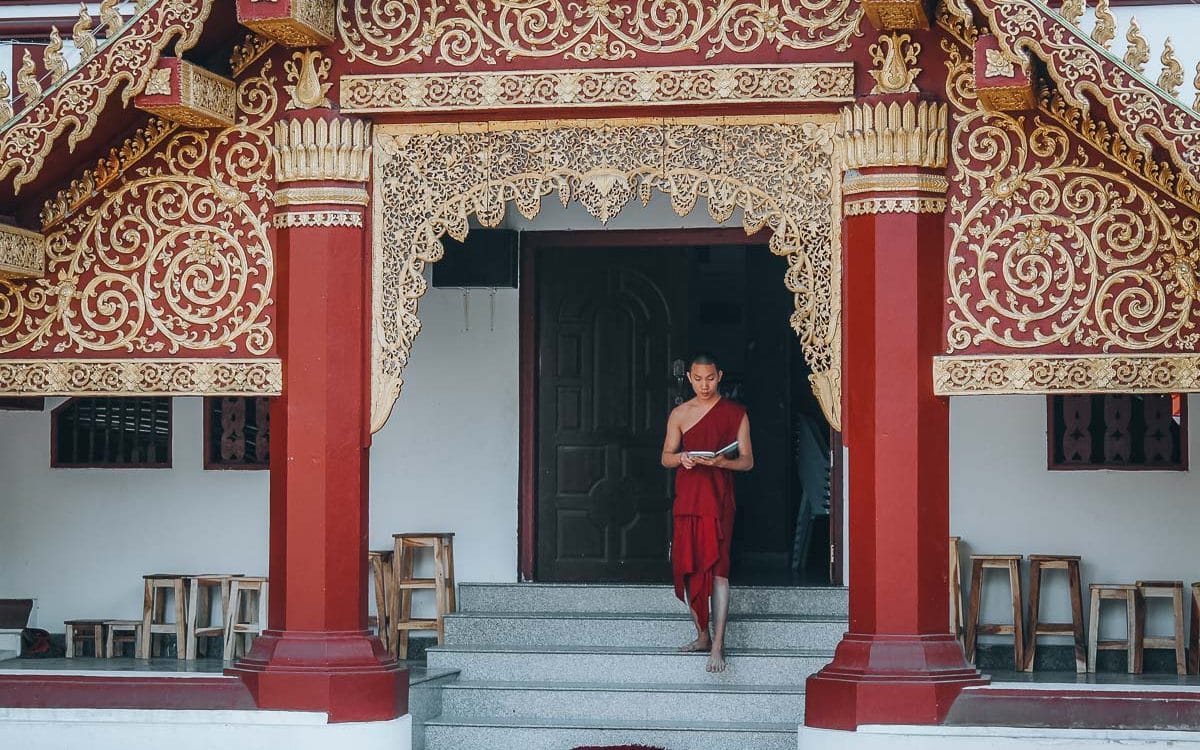 moine descendant les marches d'un temple en thailande