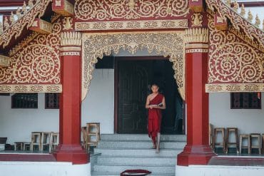 moine descendant les marches d'un temple en thailande