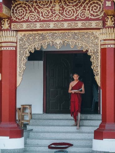 moine descendant les marches d'un temple en thailande
