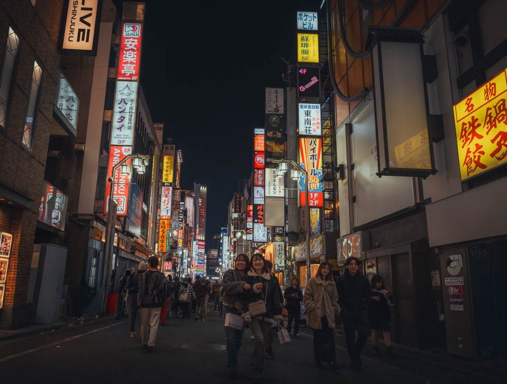 Perspective d'une rue vivante de Kabukicho à Tokyo bordée d'enseignes publicitaires verticales et de néons colorés