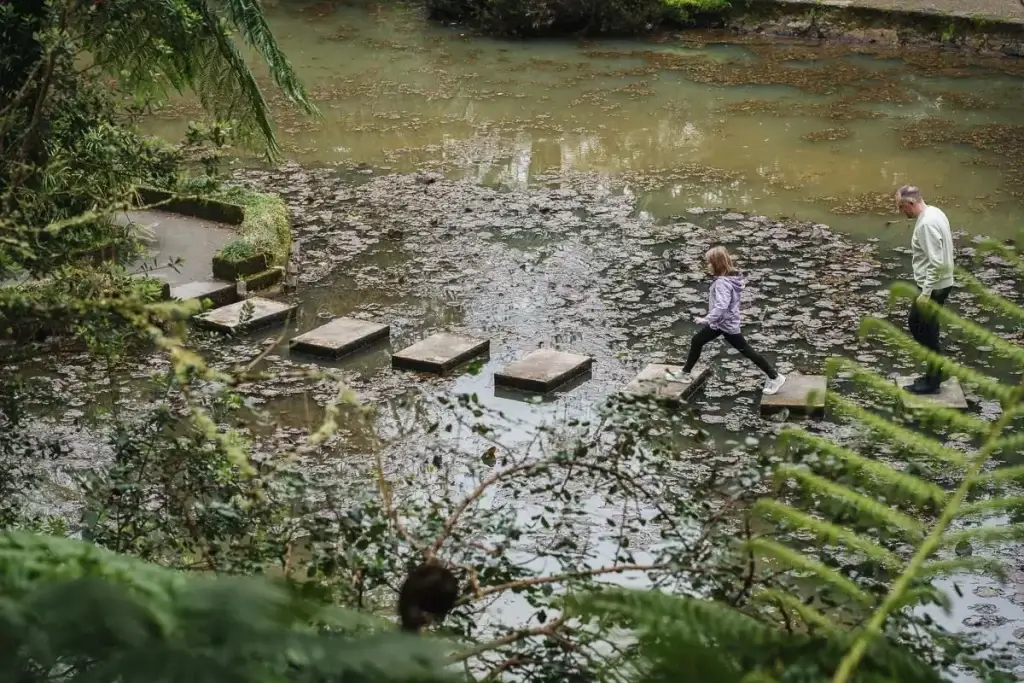 Enfant sautant sur les pas japonais d'un bassin dans le parc Terra Nostra à Furnas aux Açores
