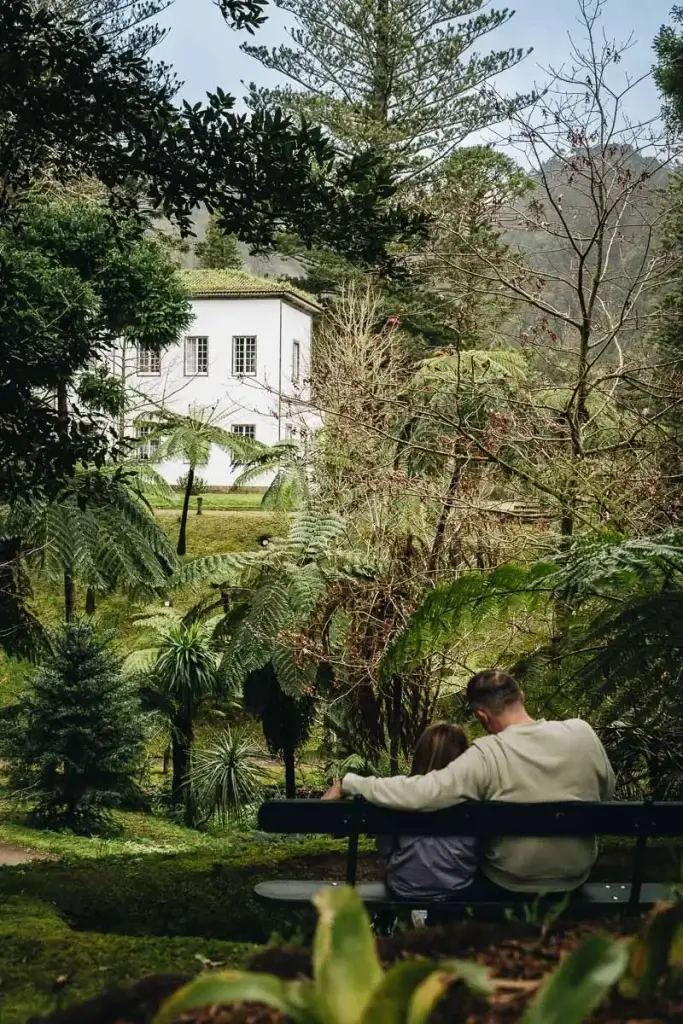 Famille assise sur un banc face à la végétation du parc Terra Nostra à Furnas à São Miguel