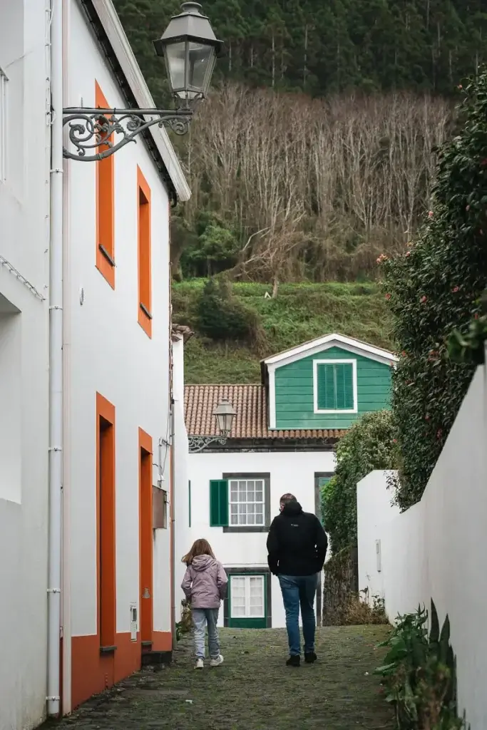 Père et fille dans une ruelle aux maisons à volets colorés à Pico aux Açores