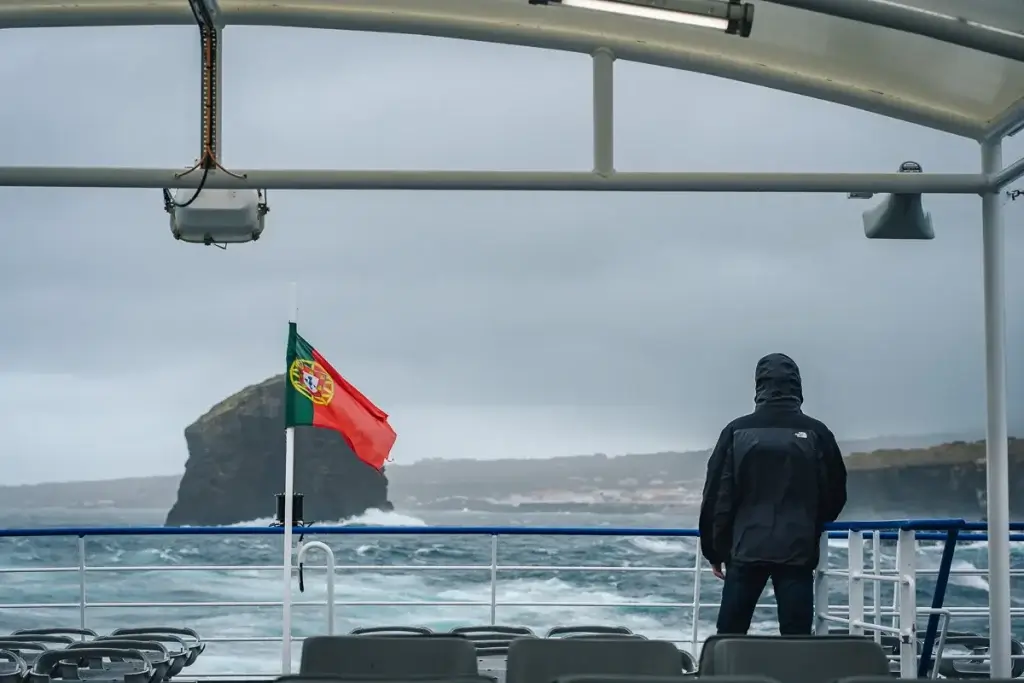 Passager sur le ferry entre Pico et Faial aux Açores sous la pluie, drapeau portugais et mer agitée