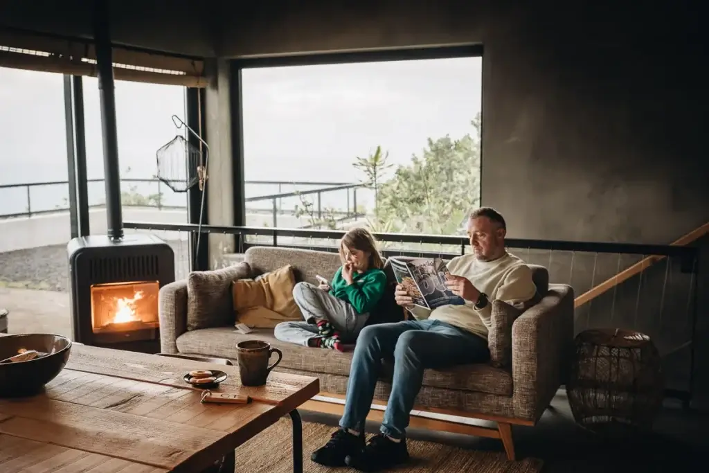 Famille au coin du feu dans le salon des Lava Homes sur l'île de Pico aux Açores, ambiance cosy et chaleureuse