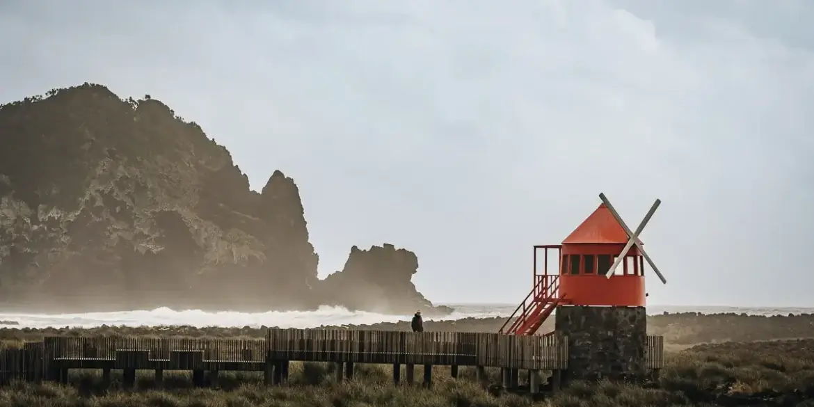 Moulin à vent rouge face aux vagues sur la côte de Pico aux Açores