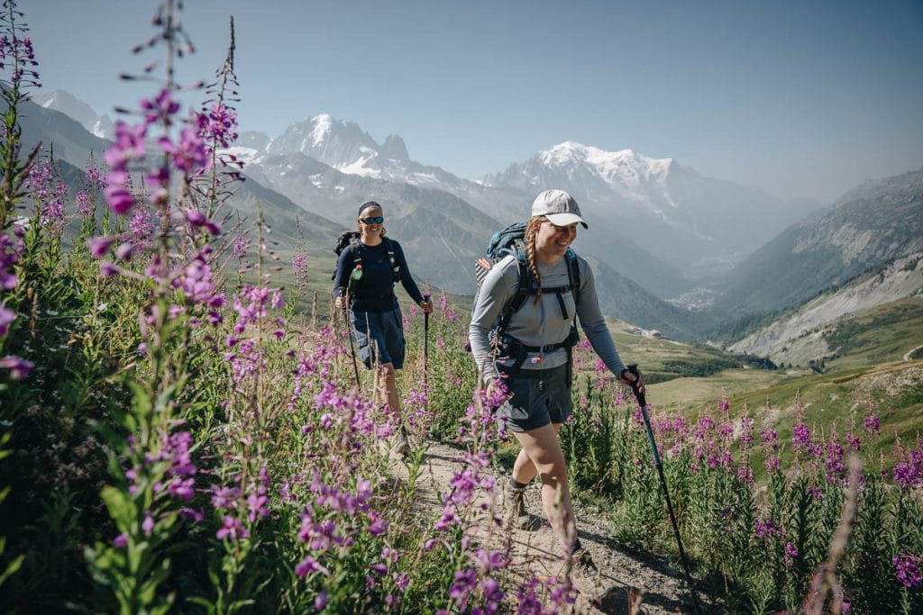 Deux randonneuses souriantes arpentant le sentier fleuri lors de la descente vers Chamonix