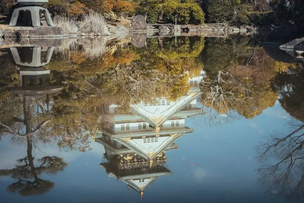 Reflet du château d’Osaka dans l’étang du jardin, entouré d’arbres aux couleurs dorées