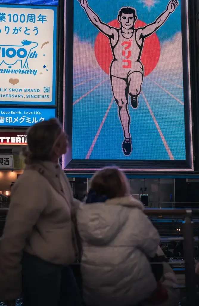 Mère et fille de dos face au panneau du coureur Glico, à Dotonbori, Osaka