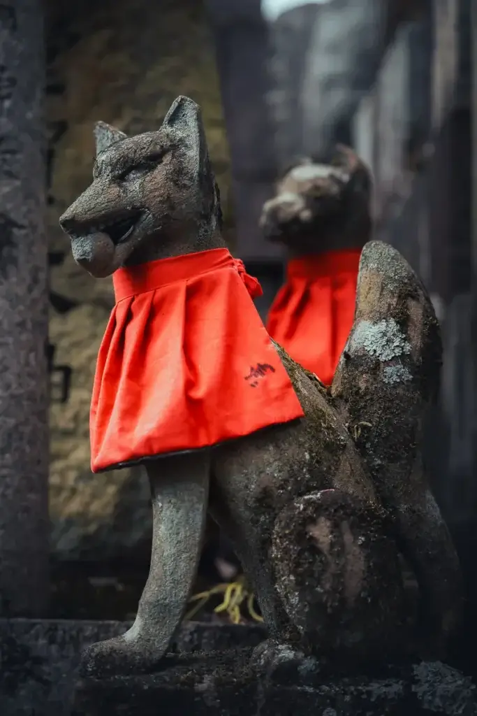 Statue de renard portant un bavoir rouge, messager du dieu Inari, au sanctuaire Fushimi Inari