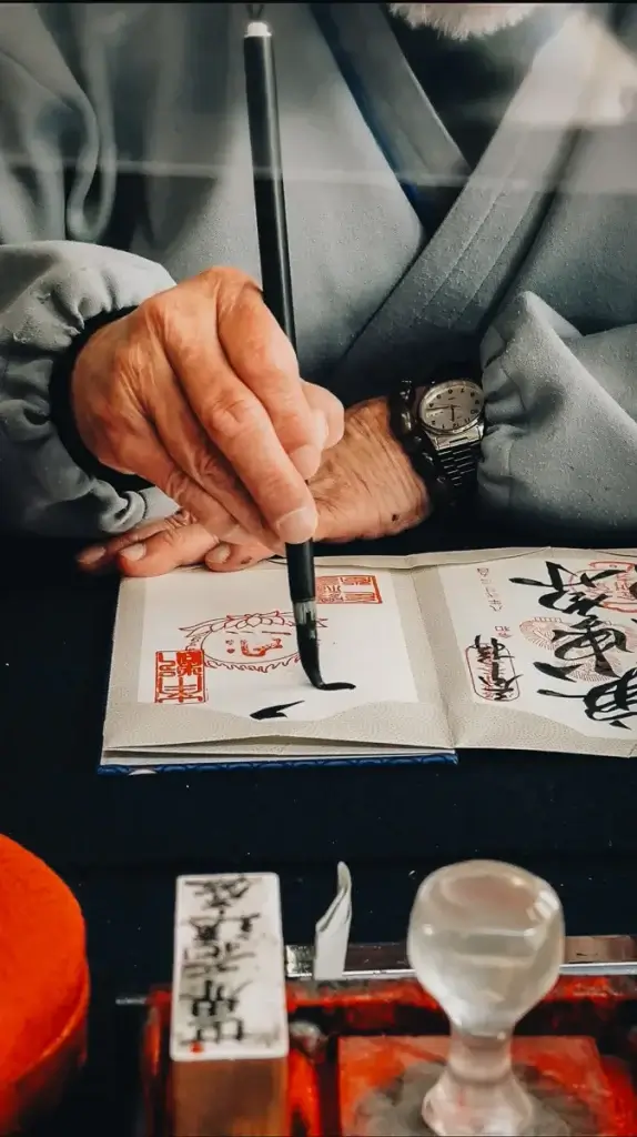 Moine calligraphiant un goshuin, le sceau du temple, au pavillon Nan'endō de Kōfuku-ji à Nara