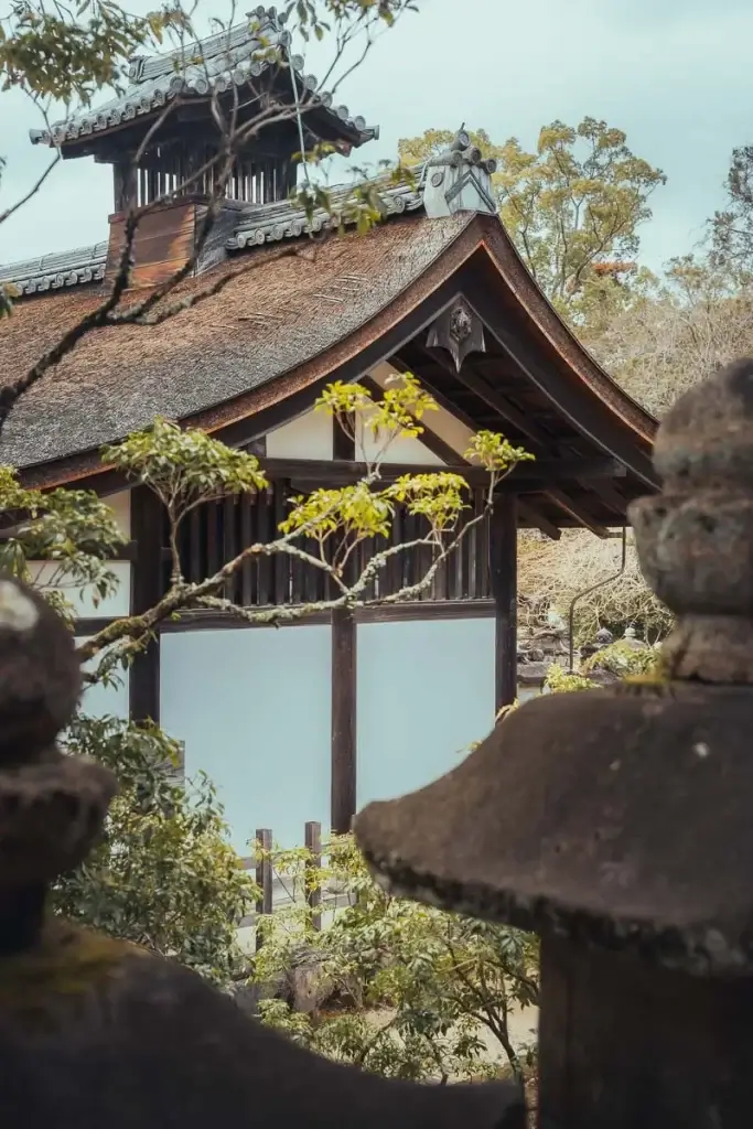 Bâtiment au toit de chaume du sanctuaire Kasuga Taisha à Nara, vu entre deux lanternes de pierre couvertes de mousse