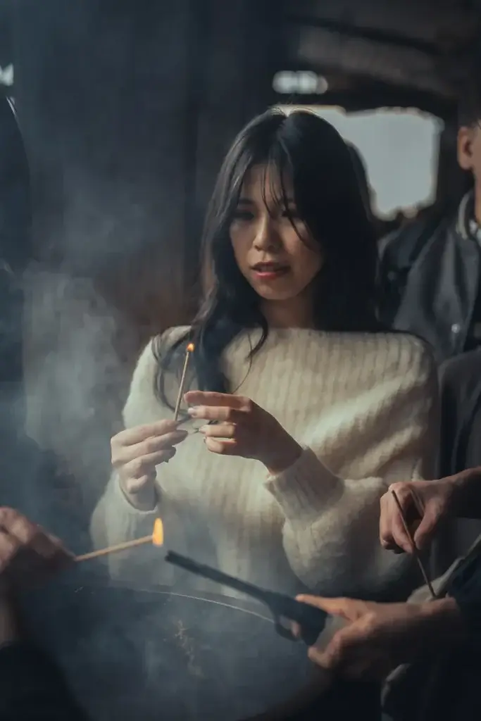 Visiteuse allumant un bâton d'encens dans la fumée du grand brûleur du Kiyomizu-dera, à Kyoto