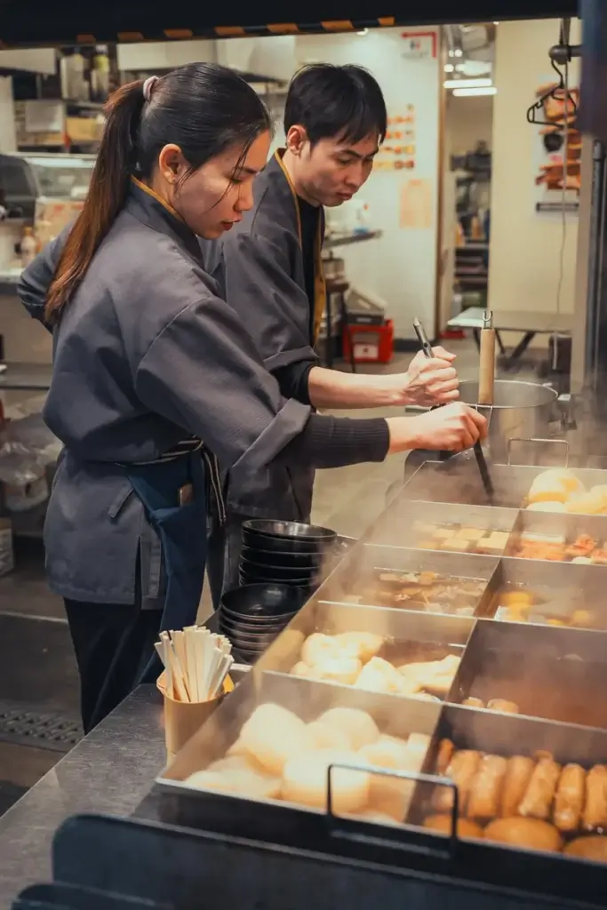 Cuisiniers servant de l’oden mijoté au marché Kuromon d’Osaka