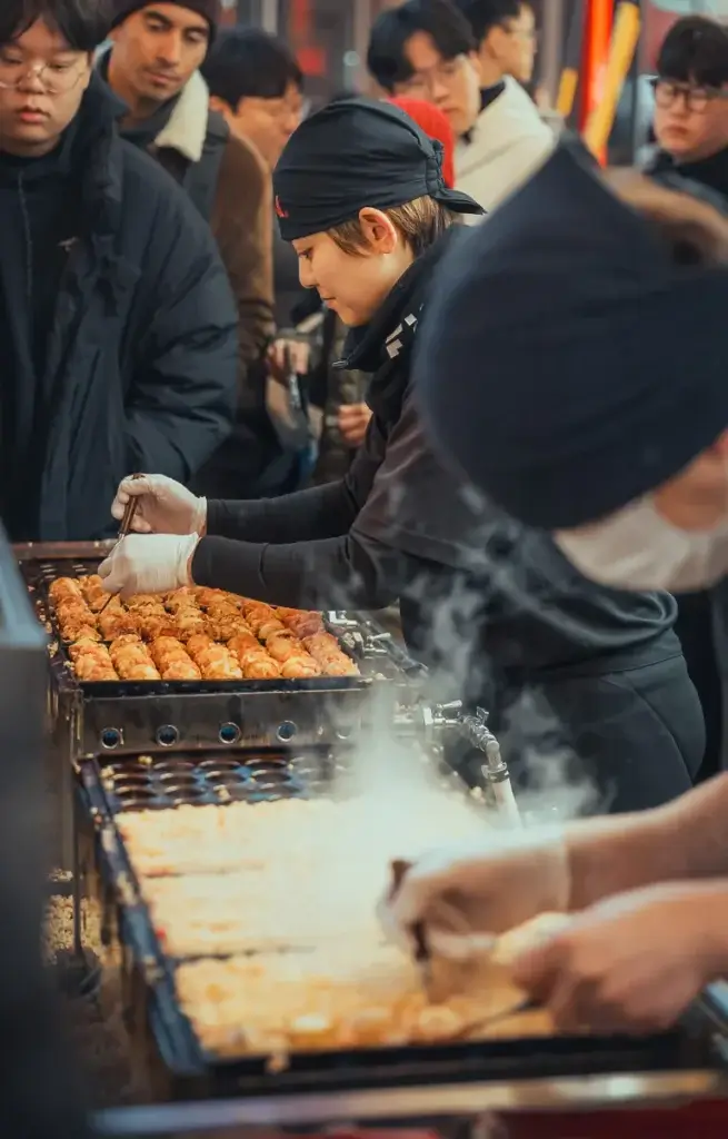 Cuisinière retournant des takoyaki sur une plaque chaude à un stand d’Osaka